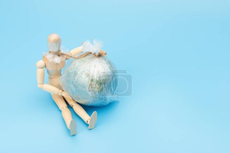 .World Environment Day concept. Symbol wooden man and planet earth globe. The consequence of environmental pollution will be the death of mankind.