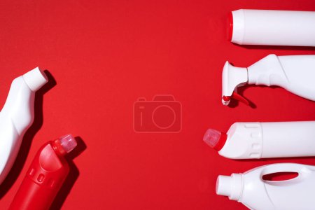 Cleaning products on red background. Top view. Copy space. Chemical cleaning supplies. Stop plastic, recycling, separate collection of garbage concept