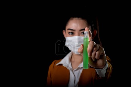 Businesswoman of young Asia woman putting on a respirator N95 mask with the hand that applying alcohol spray from the plastic bottle or anti bacteria to prevent the spread of germs at black background