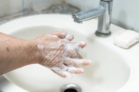 Asian senior or elderly old lady woman patient washing hand by soap and clean water for protect infection and kill Novel Coronavirus (2019-nCoV) Covid-19 virus, bacteria and germs.