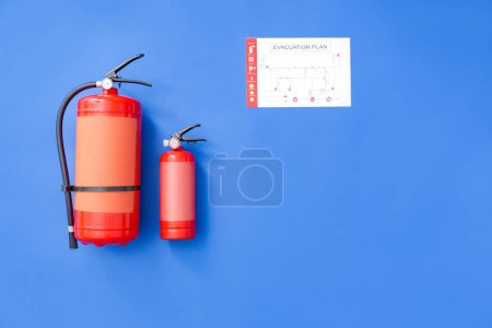 Fire extinguishers and evacuation plan on color background