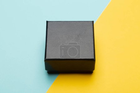 Mini black box product packaging isolated on yellow half blue background.