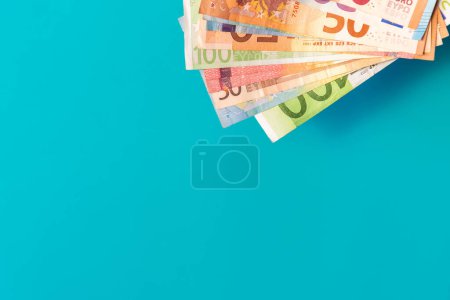 Euro banknotes isolated on blue background with soft shadows. Euro notes in corner on azure background with copy space. Euro cash of different values. Bunch of European money.