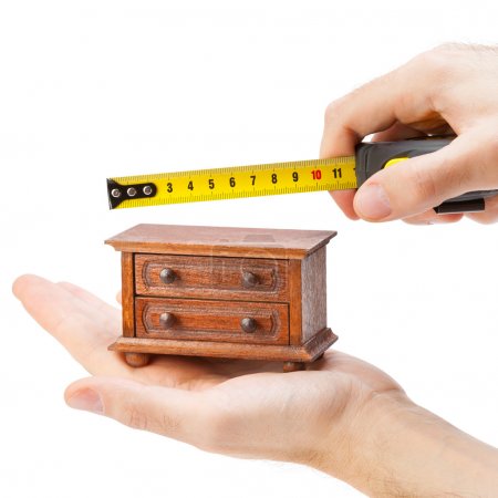 Woodworker measuring chest of drawers with a tape measure, carpe