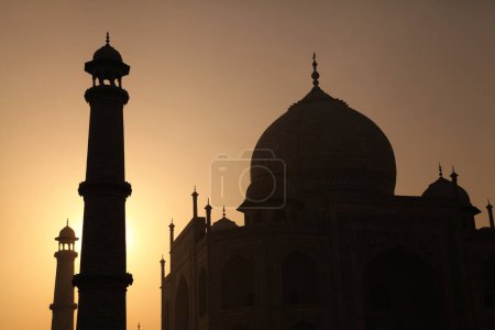 Silhouette of the Taj Mahals main complex with two minarets during sunrise in Agra, Uttar Pradesh.