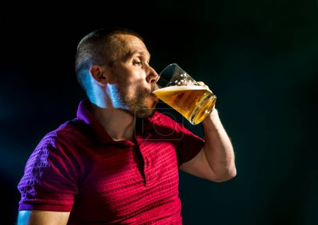 man enjoys drinking beer from a mug on a dark green background