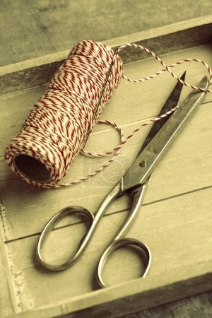 Scissors and spool of thread on wooden tray