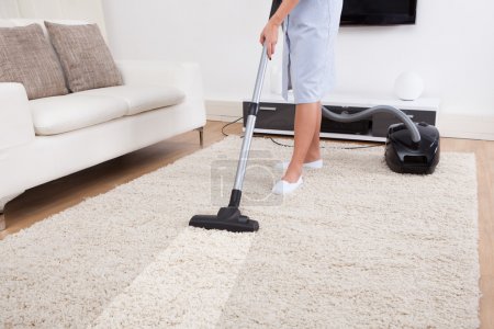 Maid Cleaning Carpet With Vacuum Cleaner