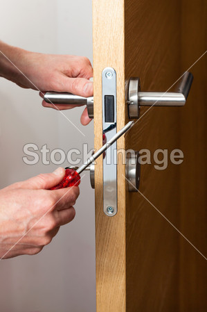 Hands repairing a door lock
