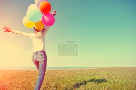Young woman running with colored balloons