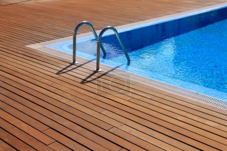Blue swimming pool with teak wood flooring
