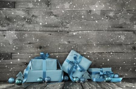 Grey wooden christmas background with a stack of presents in blu