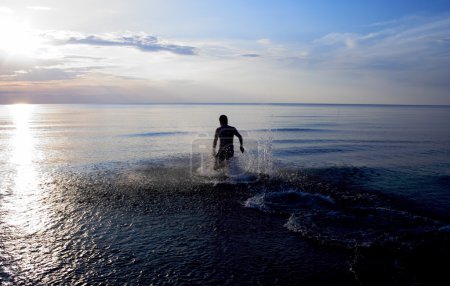 Man standing in sea at late evening