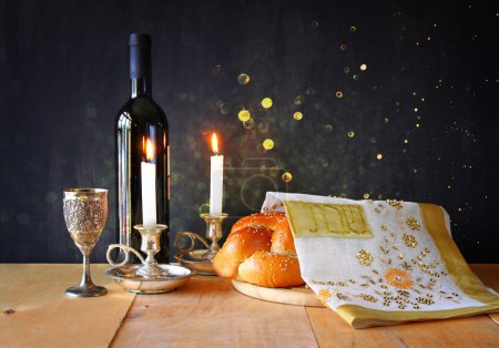 Sabbath image. challah bread and candelas on wooden table. glitter overlay