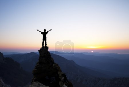Man on top of the mountain reaches for the sun
