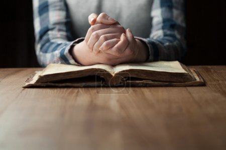 Woman hands praying with a bible