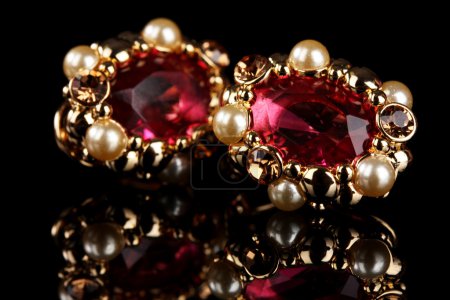 Beautiful gold earrings with rubies and pearls on black background