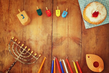 top view image of jewish holiday Hanukkah with menorah (traditional Candelabra), donuts and wooden dreidels (spinning top). retro filtered image.