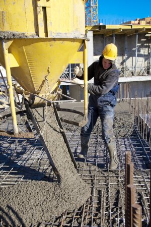 Builder worker during concrete pouring works at construction site