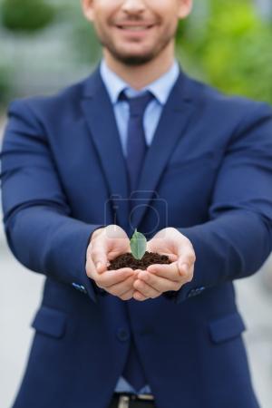 Pleasant businessman holding ground in hands