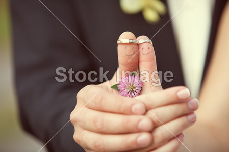 Wedding rings on her fingers painted with the bride and groom, f