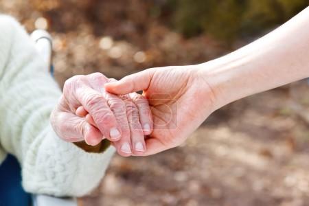 Senior Lady Holding Hands with Young Caretaker