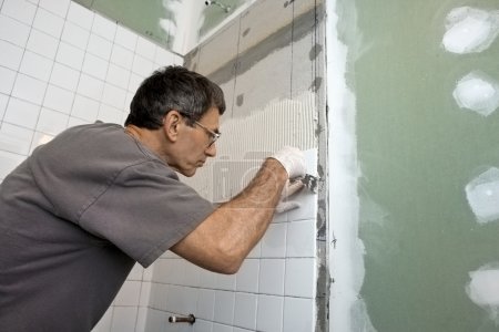 Man Tiling A Bathroom Wall