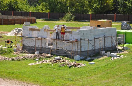 Building house from aerated concrete building blocks. Builders laying blocks.